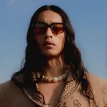 Model wearing Tejesta Seminole sunglasses in the desert, showcasing the bold rectangular frame with Art Deco details.