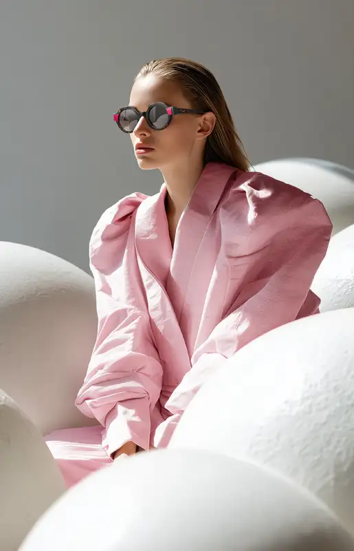 Model in pink wearing ATELIER by Woodys FW25 sunglasses from the Woodys FW25 collection, showcasing premium handcrafted eyewear.