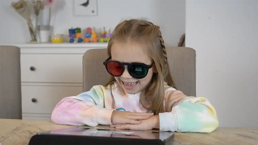 Child smiling while completing exercises in the AmblyoPlay vision therapy program, showing positive engagement during binocular training.